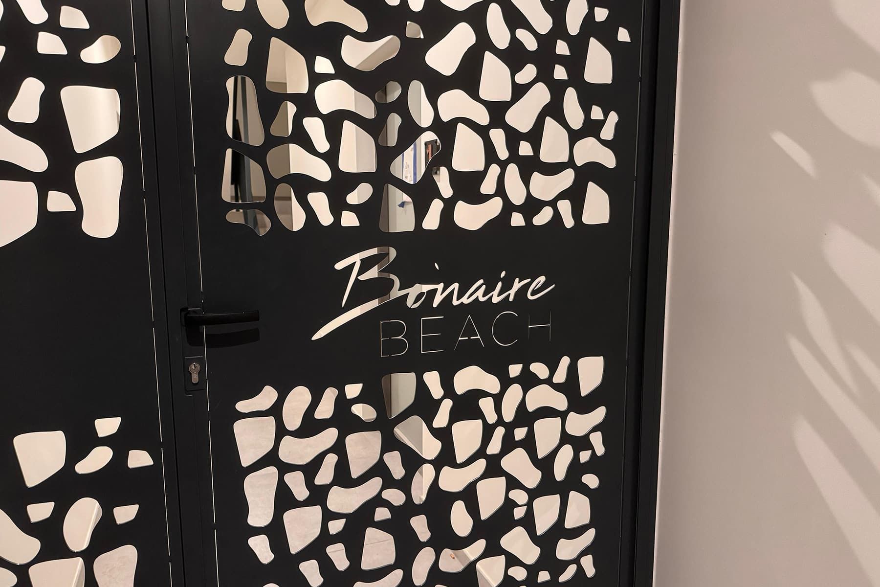 A door with a black frame and white abstract patterns, labeled "Bonaire Beach".