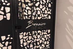 Une porte dotée d’un cadre noir et de motifs abstraits blancs, portant l’inscription « Bonaire Beach ».