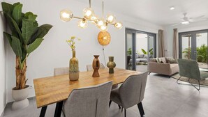 A modern dining area with a wooden table, grey chairs, and a unique spherical chandelier.