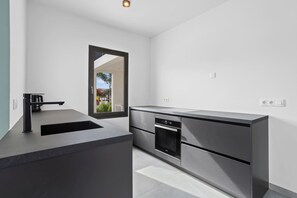 A modern kitchen with a built-in oven, a sink, and a large window.