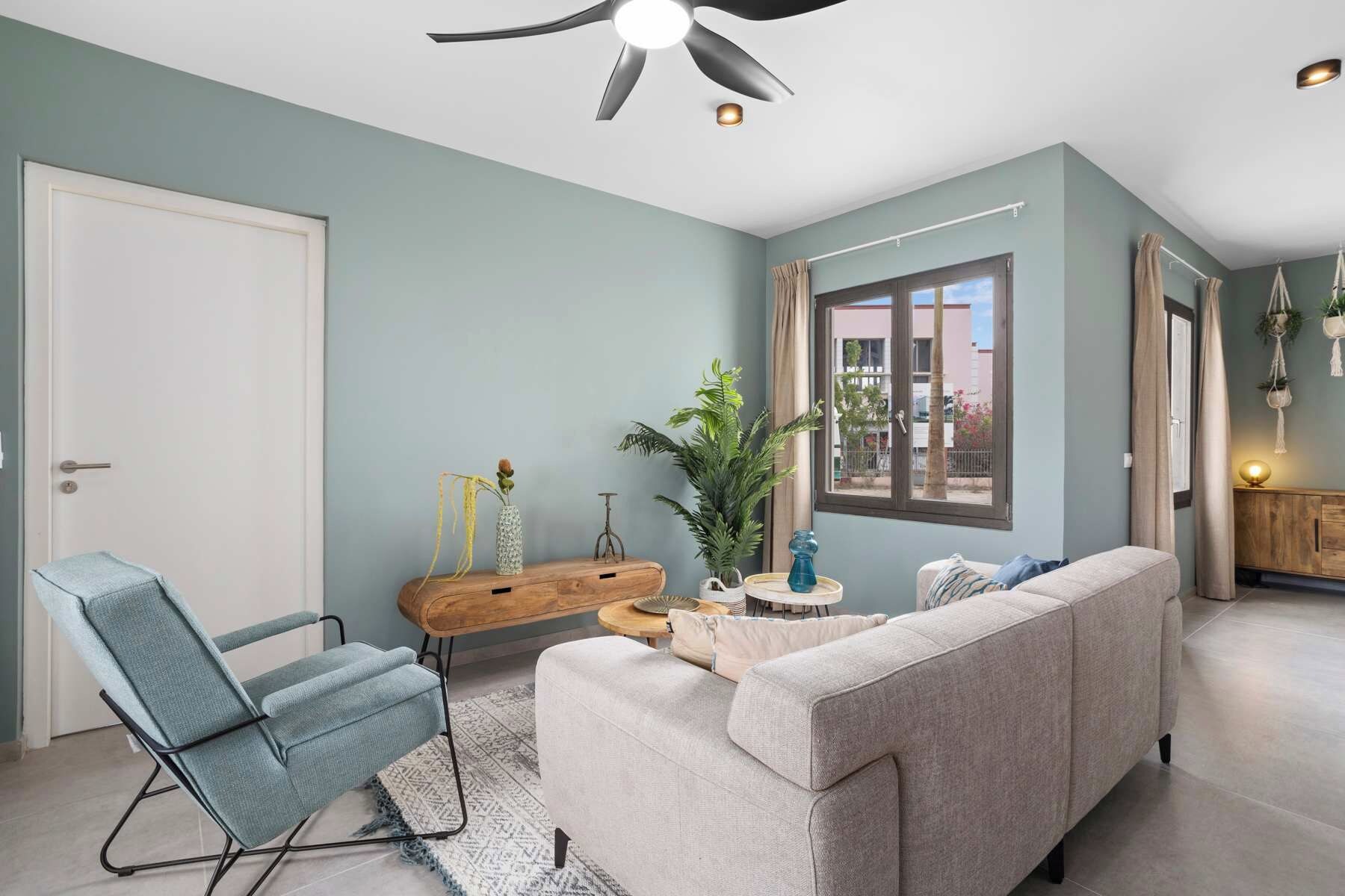 A living room with a sofa, a chair, a wooden side table, and a potted plant.