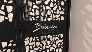 Una puerta con marco negro y diseños abstractos blancos, con la leyenda "Bonaire Beach".