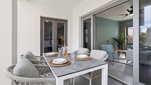 Un coin repas avec une table dressée pour deux personnes, une chaise en osier et un canapé.