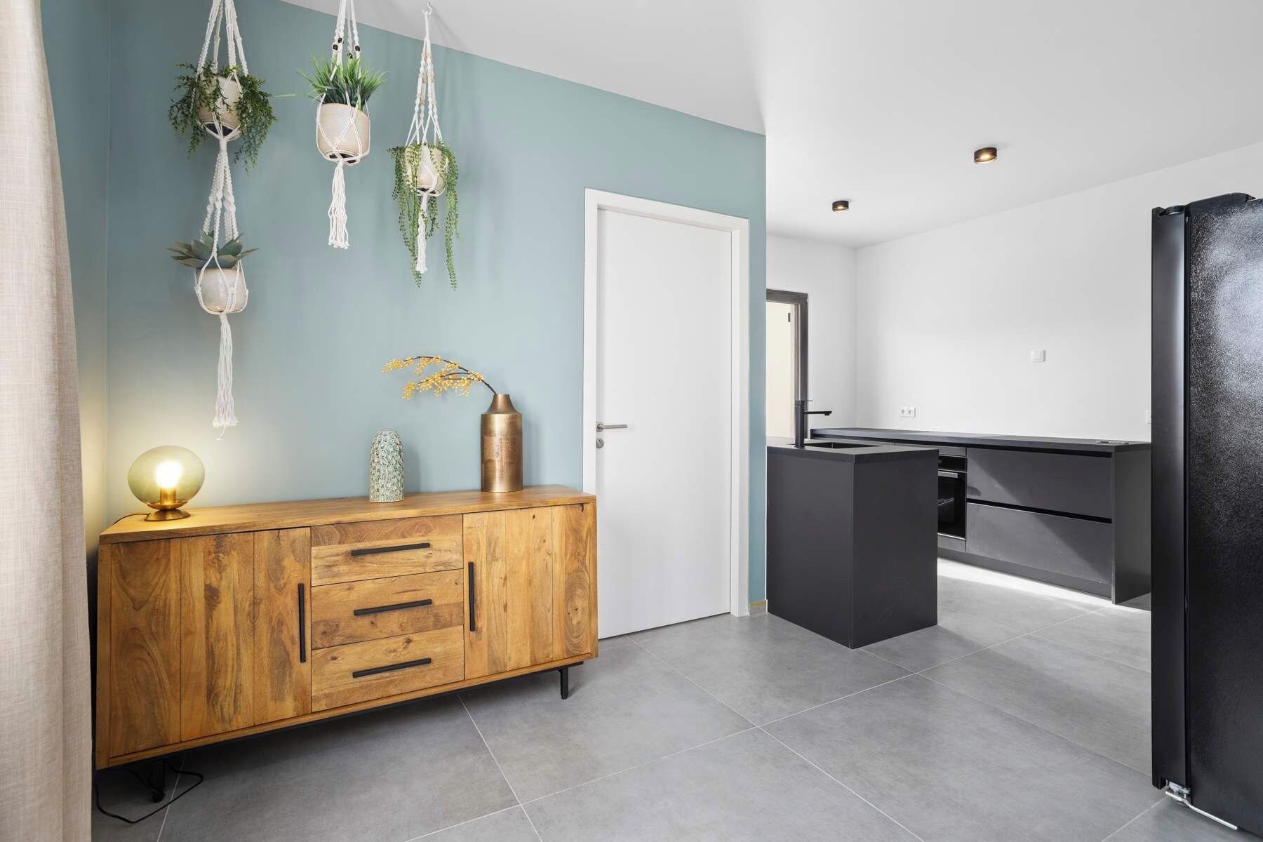 Una cocina moderna con un armario de madera, un refrigerador negro y una pared azul decorativa.