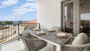 A balcony with a table set for two, overlooking a coastal area. - Bonaire Beach Apartments 6 with a refreshing shared pool and ocean view (Kralendijk)