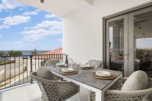 A balcony with a table set for two, overlooking a coastal area. - Bonaire Beach Apartments 6, ocean view, pool (Kralendijk)