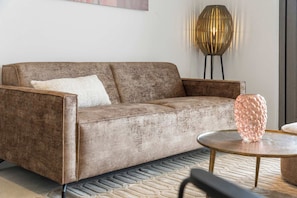 A modern living room with a brown sofa, a round coffee table, and a decorative vase. - Bonaire Beach Apartments 6 with a refreshing shared pool and ocean view (Kralendijk)