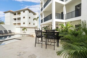 A modern apartment building with a swimming pool, outdoor seating, and lush greenery. - Bonaire Beach Apartments 6 with a refreshing shared pool and ocean view (Kralendijk)