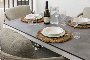 A dining table set with white plates, clear glasses, a bottle of Prosecco, and a pitcher of water. - Bonaire Beach Apartments 6, ocean view, pool (Kralendijk)