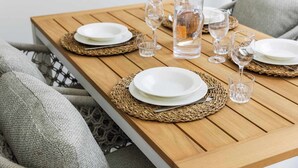 A wooden dining table set with white plates, clear glasses, and a bottle of champagne. - Bonaire Beach Apartments 7 centrally located with sea views (Kralendijk)