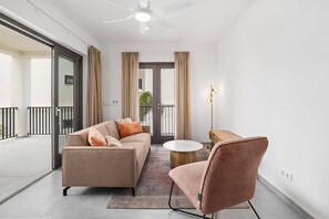 A modern living room with a sofa, armchair, and coffee table, a ceiling fan, and a view of a balcony. - Bonaire Beach Apartments 7 centrally located with sea views (Kralendijk)