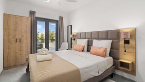 A bedroom with a bed, a wardrobe, a ceiling fan, and a view through the window. - Bonaire Beach Apartments 7 centrally located with sea views (Kralendijk)