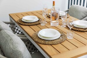 Ein Holztisch ist mit weißen Tellern, klaren Gläsern und einer Champagnerflasche gedeckt.