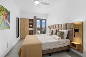 Un dormitorio moderno con una cama grande, un armario, un balcón con vistas y un ventilador de techo.