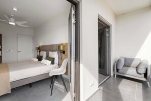 Una habitación de hotel moderna con cama, escritorio, silla y sofá.