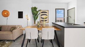 Een moderne keuken met een eethoek, met een houten tafel, twee stoelen, een vaas met bloemen en een groot raam met uitzicht.