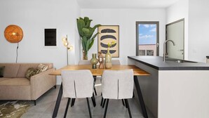 Een moderne keuken met een eethoek, met een houten tafel, twee stoelen, een vaas met bloemen en een groot raam met uitzicht.