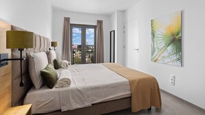 Een moderne slaapkamer met een bed, een plafondventilator en een groot raam met gordijnen.