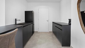 A compact kitchen with dark cabinetry, a sink, and a coffee machine. - Bonaire Beach Apartments 10 with a refreshing shared pool and spectacular sea views (Kralendijk)
