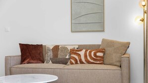 A neutral-toned sofa with four patterned cushions, a marble table, and a modern floor lamp. - Bonaire Beach Apartments 10 with a refreshing shared pool and spectacular sea views (Kralendijk)