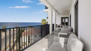 A balcony with a view of the sea, a sofa, and a table with chairs. - Bonaire Beach Apartments 10 with a refreshing shared pool and spectacular sea views (Kralendijk)