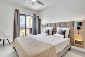 A modern hotel room with a large bed, a balcony, and a view of the city. - Bonaire Beach Apartments 15 with a refreshing shared pool and spectacular sea view (Kralendijk)