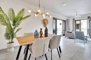 A modern dining area with a wooden table, four chairs, and a unique chandelier. - Bonaire Beach Apartments 15 with a refreshing shared pool and spectacular sea view (Kralendijk)