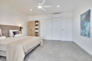 A bedroom with a bed, a wardrobe, a ceiling fan, and an air conditioning unit.