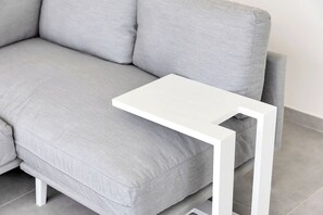 Ein graues Sofa mit einem weißen Beistelltisch.