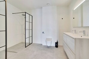 A modern bathroom with a glass shower enclosure, a toilet, and a sink with a mirror. - Bonaire Beach Apartments 15 with a refreshing shared pool and spectacular sea view (Kralendijk)