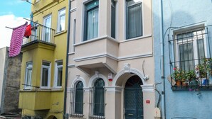 Une rangée d’immeubles à plusieurs étages dotés de balcons, un système d’alarme incendie bien visible et une rue avec un trottoir pour les piétons.