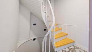 Un escalier en colimaçon avec des rampes blanches et des marches jaunes.