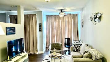 A living room with a television, a sofa, a coffee table, and a ceiling fan.