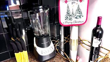 A kitchen counter with a blender, a wine bottle, and a festive card.