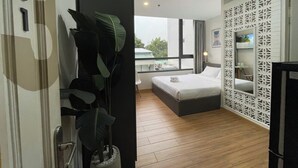 Una habitación de hotel moderna con una cama grande, un balcón con vistas y un panel blanco decorativo.