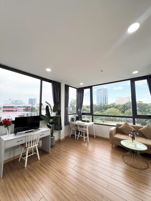 A modern living room with a TV, dining area, sofa, and large windows offering a city view. - Home Away Dang Thi Nhu (Ho Chi Minh City)
