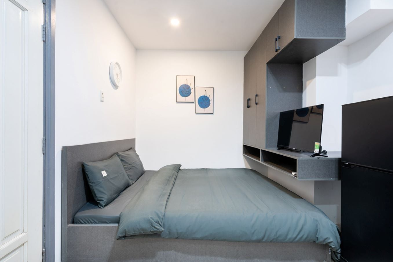 A modern bedroom with a bed, a TV, and a built-in wardrobe.