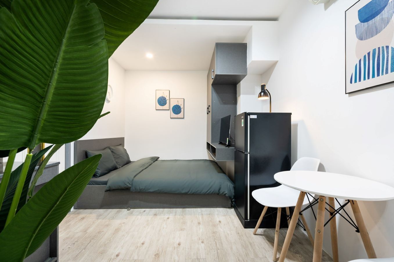 Une chambre à coucher de taille réduite, comprenant un lit, une petite table et un réfrigérateur.