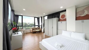 Un dormitorio moderno con una cama grande, un sofá, un escritorio y vistas a la ciudad.