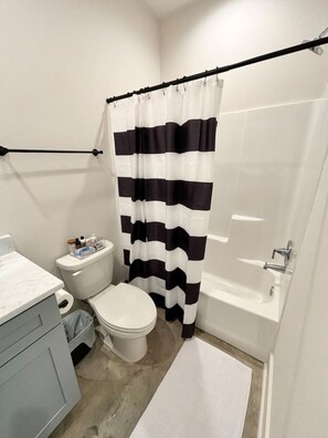 A bathroom with a white toilet, a white sink, and a bathtub. - NEW-Teche House-KING Bed-Cajun Getaway-Fast Wi-Fi (Lafayette)