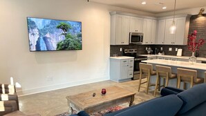 Un salon moderne avec une grande télévision, une table basse et un canapé bleu.