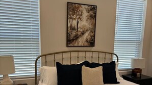 Ein Schlafzimmer mit einem Bett, zwei Nachttischen, einer Lampe und einem Bild an der Wand.