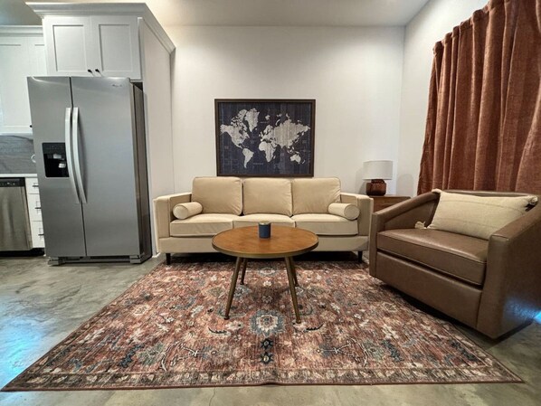 Una sala de estar con un sofá beige, un sofá marrón, una mesa de centro y un mapa mundial en la pared.