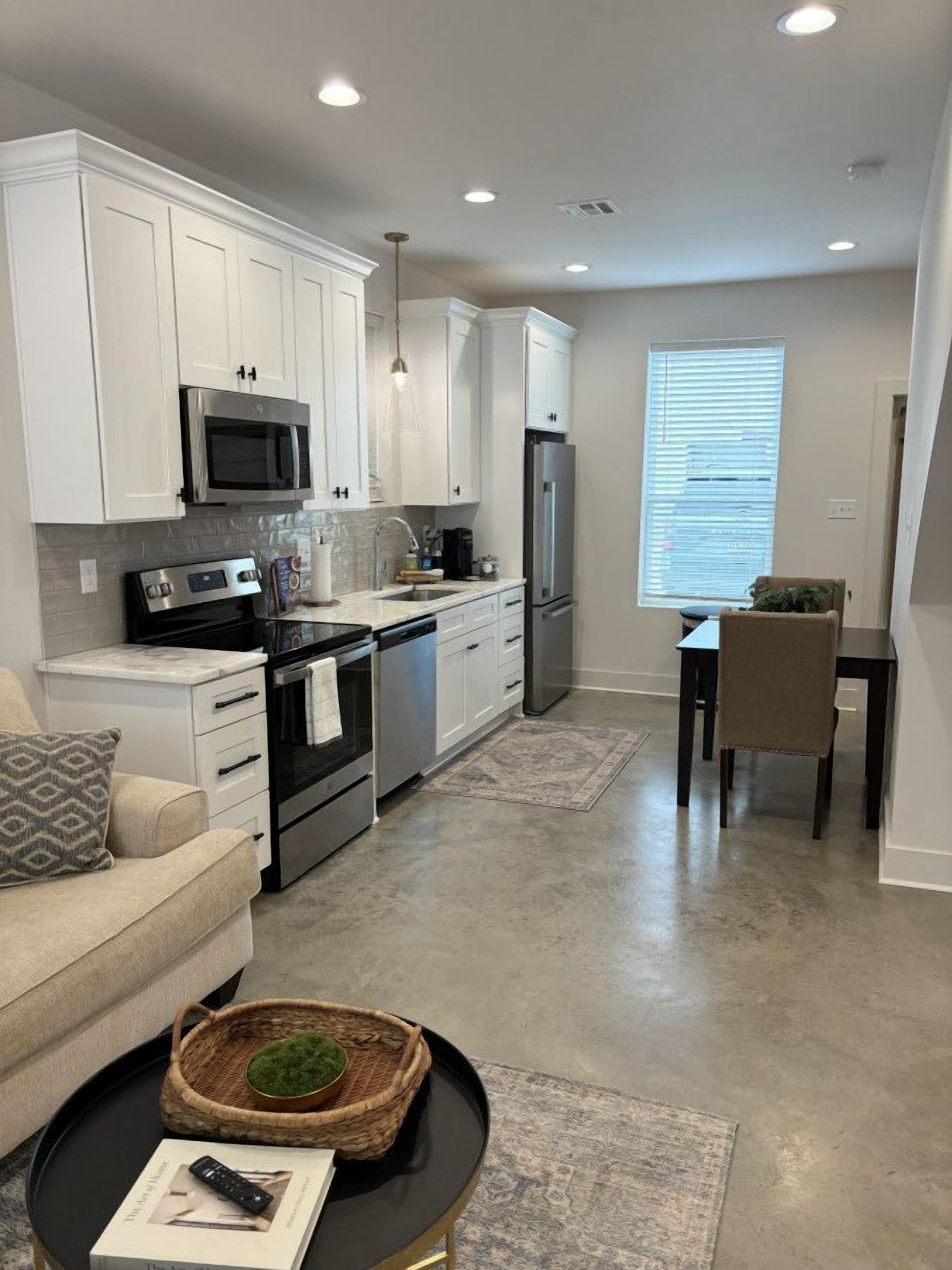 A modern kitchen with white cabinets, stainless steel appliances, and a dining area with a table and chairs.