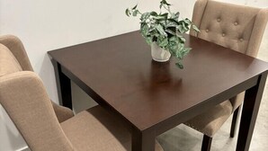 A dining table with four beige upholstered chairs, a potted plant on the table, and a white wall with a power outlet in the background. - NEW-Beignet House-Luxe Mattress-Fast WiFi-Book Now (Lafayette)