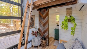 A cozy room with a wooden ladder, a herringbone-patterned wall, a green plant, and a gray sofa.
