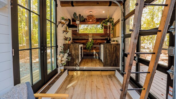 A compact kitchen with wooden cabinets, a central island, and large windows offering a view of the outdoors.