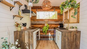 A modern kitchen with wooden cabinetry, a central island, and hanging plants.