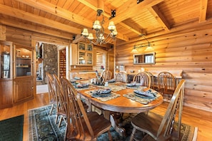 L’intérieur d’un chalet en bois, avec une table à manger dressée pour six personnes, entourée de chaises.