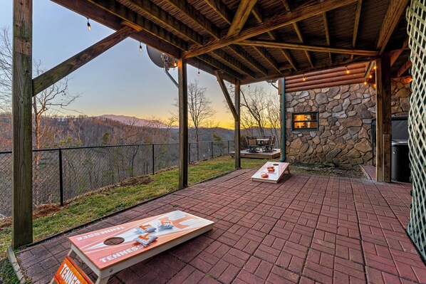 A covered patio with a stone wall, a view of the mountains, and a table with a Tennessee flag.